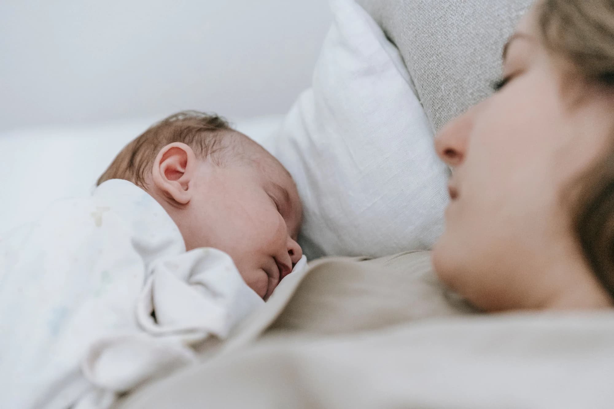 Mutter hält ihr schlafendes Neugeborenes im Wochenbett