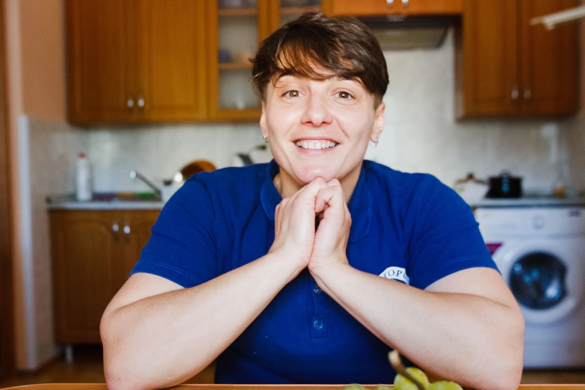 Eine lächelnde Frau im blauen Poloshirt in einer Küche