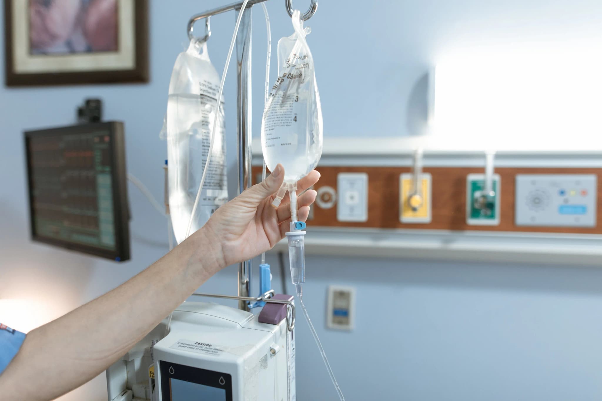 Eine Hand hält einen Infusionsbeutel am Infusionsständer