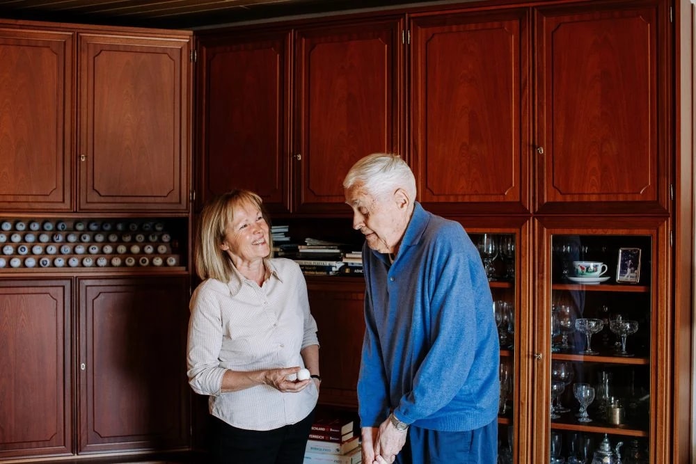 Ein Senior spricht zu Hause mit seiner Alltagsbegleiterin