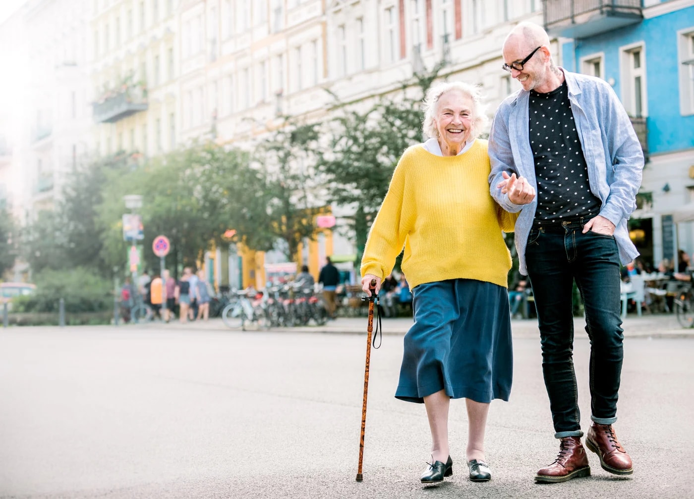 Eine Seniorin und ihr Alltagsbegleiter lachen bei einem gemeinsamen Spaziergang
