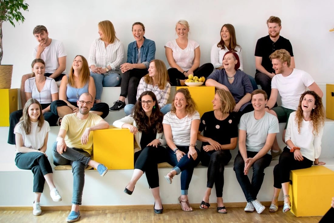 Careship-Team gemeinsam auf einer Treppe mit gelben Sitzwürfeln